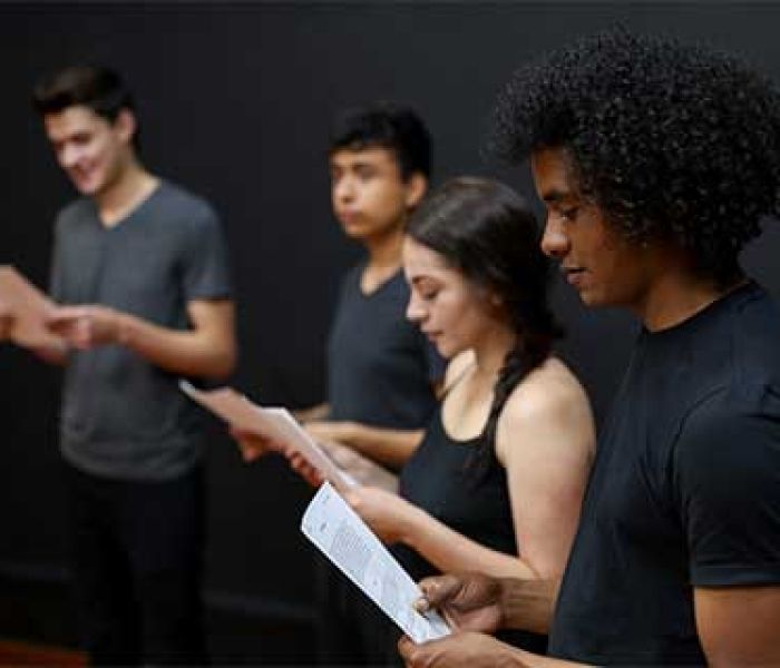 Musical Theatre student sat on a stage in the spotlight