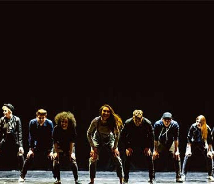 Musical Theatre students performing a dancing routine on stage under the spotlight