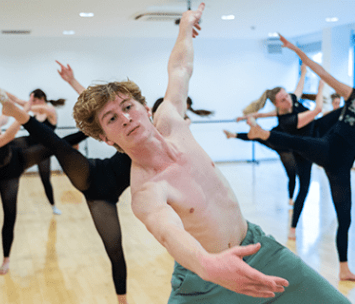 A dance student leading fellow dance students in a choreograph in the dance studios