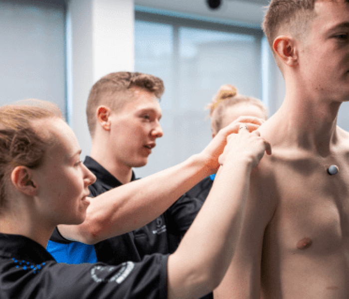 Two Sports Therapy students assessing the shoulders of a fellow student.