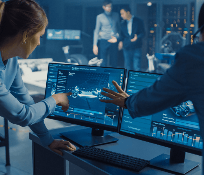 Two students pointing and looking at a computer screen which has digital drawings on.