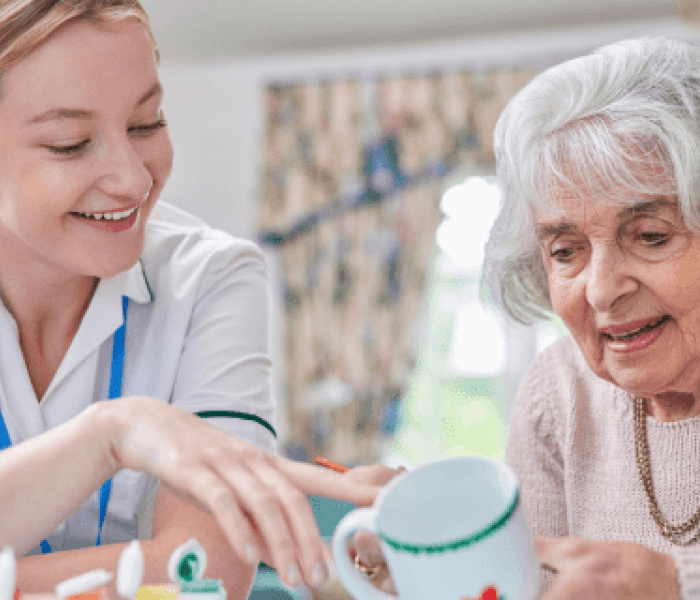 An occupational therapist sat next to an elderly patient.