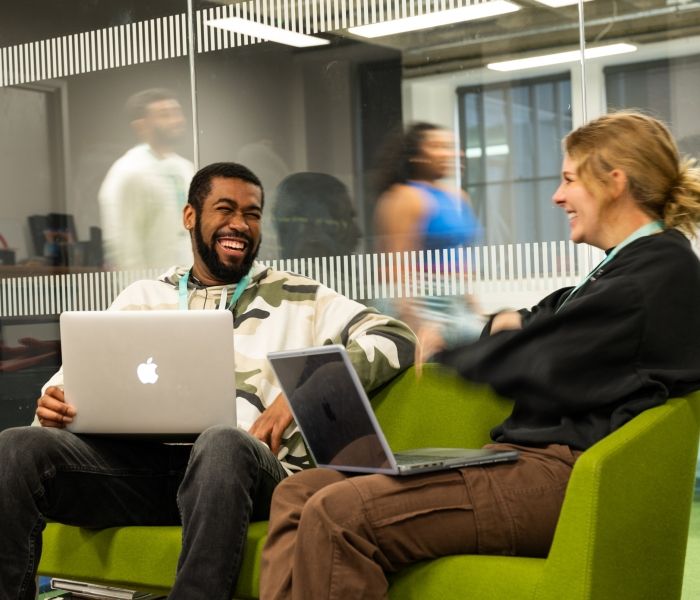 Two students with laptops in a classroom