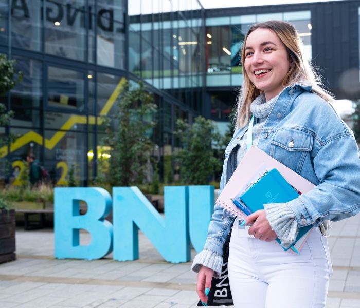 Female student outside the BNU sign at High Wycombe campus