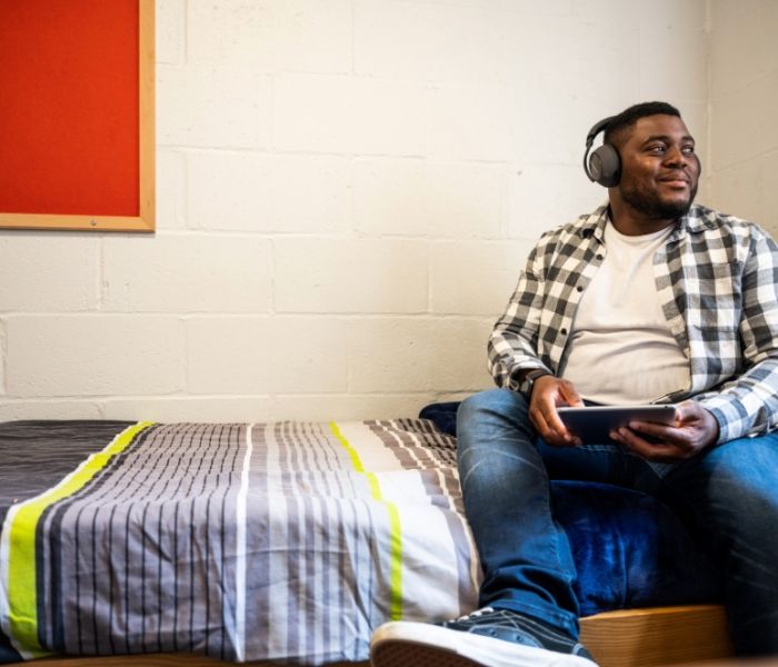 Smiling student sitting on a bed in student accommodation