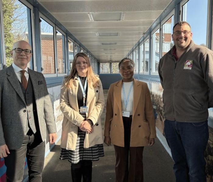 Four people stood on a bridge posing for a photo.