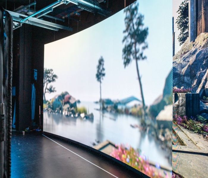 A large LED wall screen with a backdrop of a trees and water on display in a Film and TV studio.