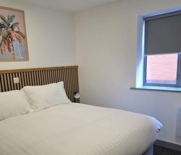 Interior of a bedroom in Alex House showing bed, wall art, window and radiator