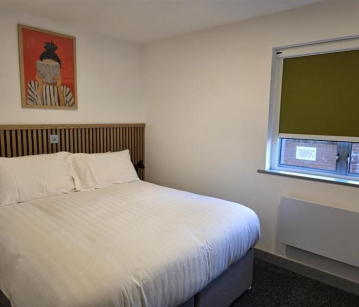 Interior of a bedroom in Alex House showing bed, wall art, window and radiator