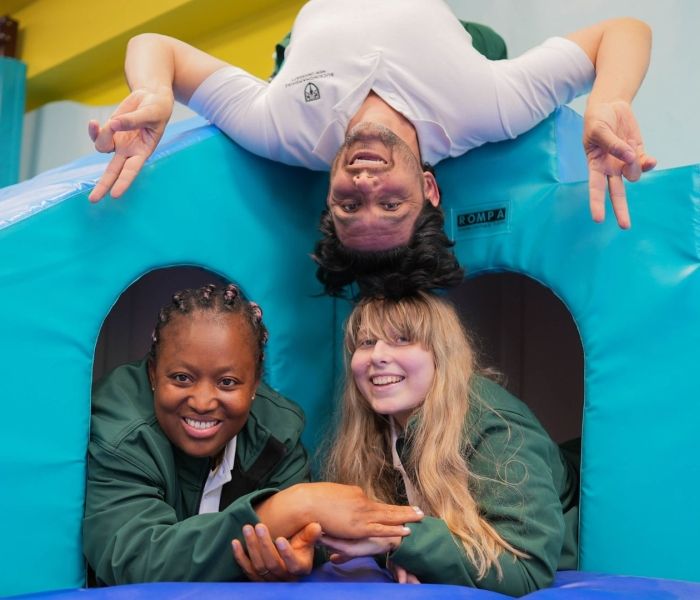 Two Occupational Therapy students laid down alongside one another as another student hands upside down.