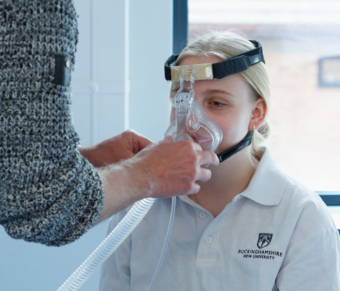 Physiotherapy student participating in a demonstration as a lecturer fits a non-invasive ventilation mask to her face