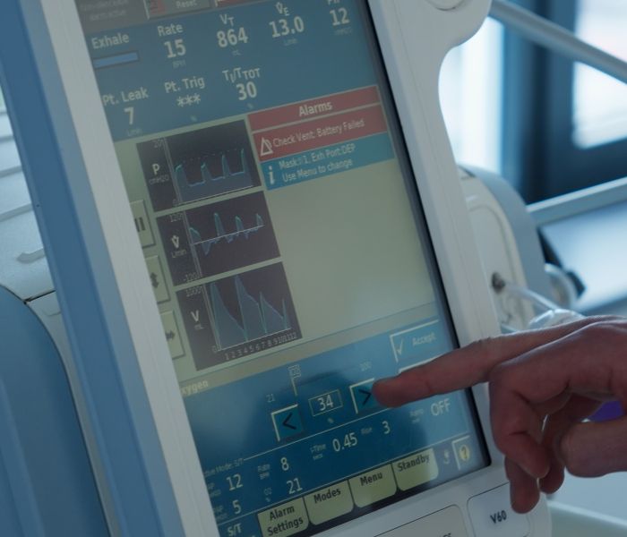 Close-up of a lecturer adjusting settings on a medical ventilator monitor screen