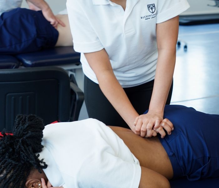 Physiotherapy student practicing manual therapy techniques on a colleague during a practical session