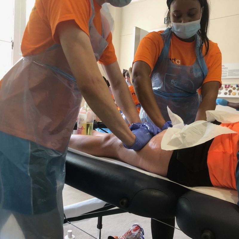 Students in MNDA uniform and PPE carrying out sports therapies on athletes