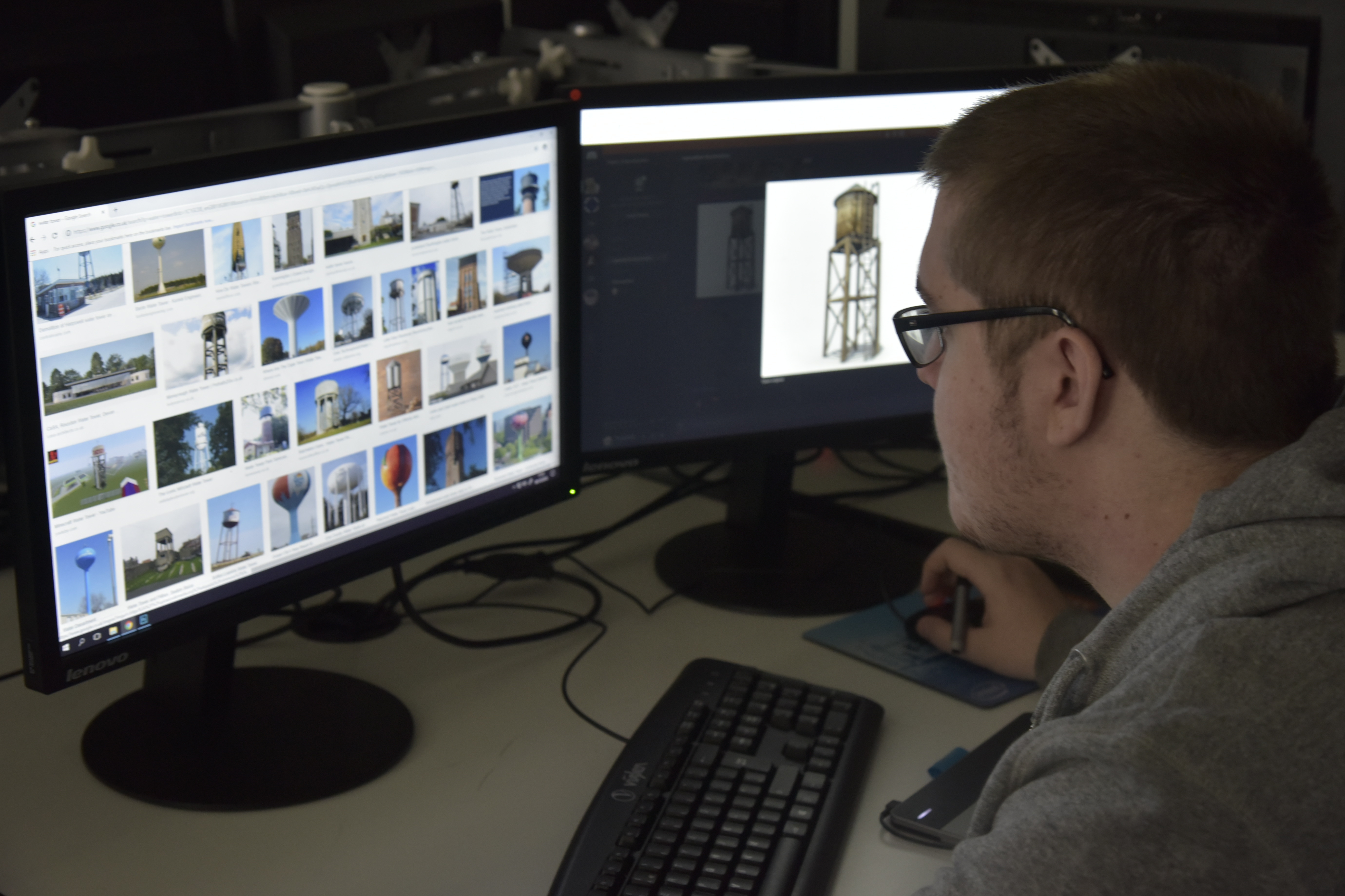 Student with glasses looking at two computer screens