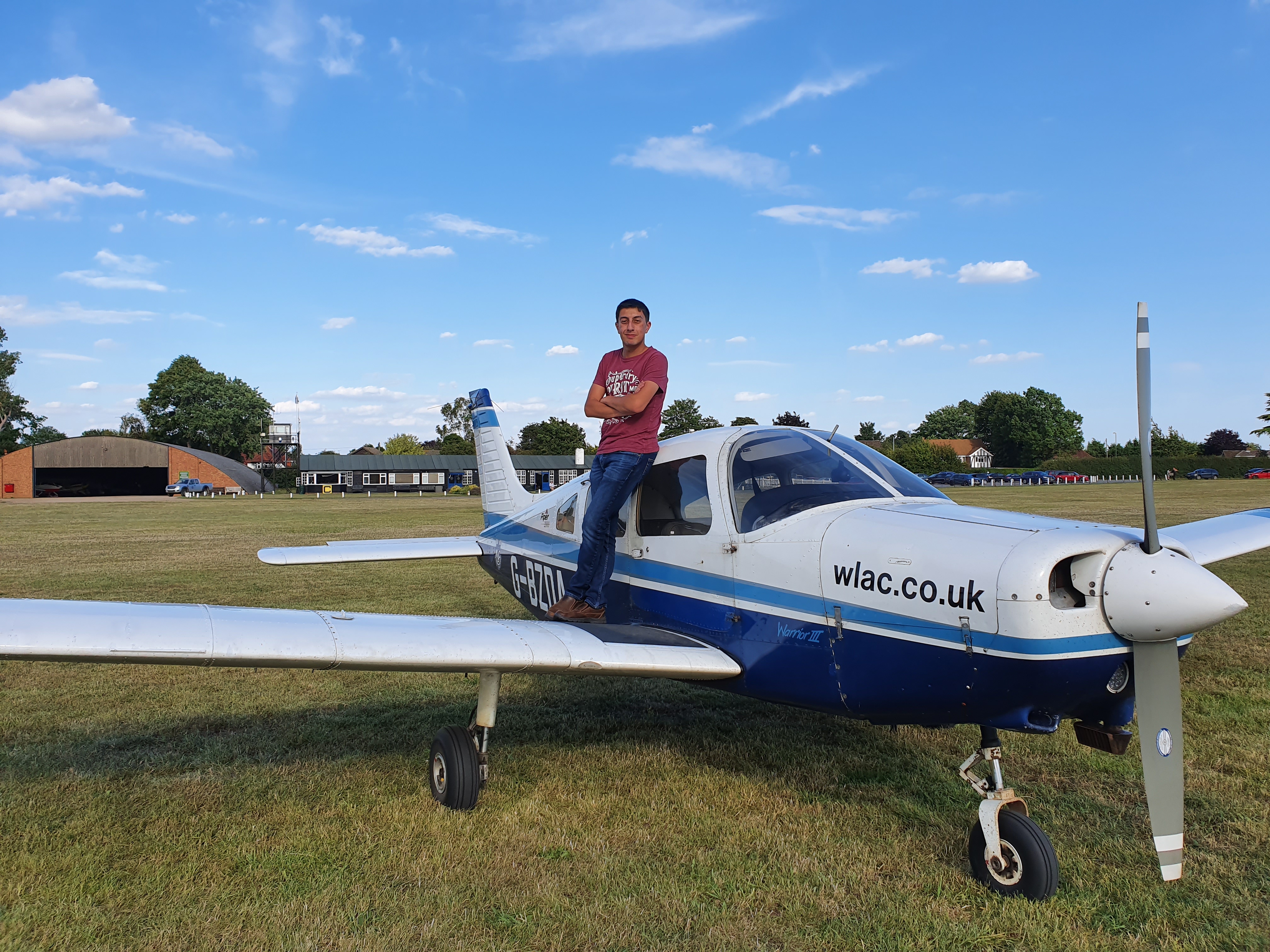 Student Jacob standing on the wing of a plane at airfield