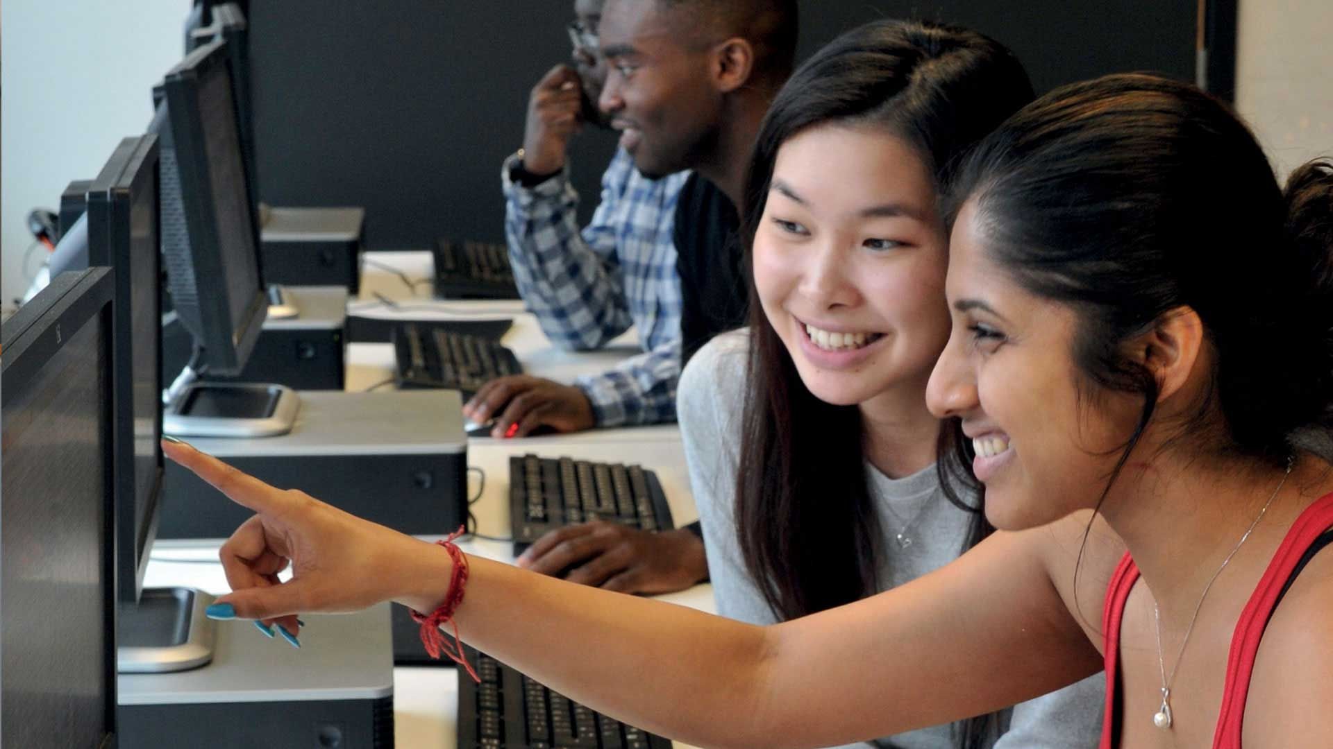 Two students smiling and looking at a computer screen