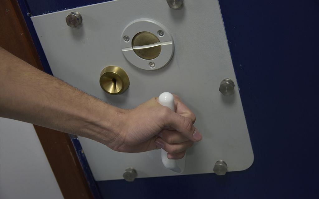 A police cell door handle being turned closed