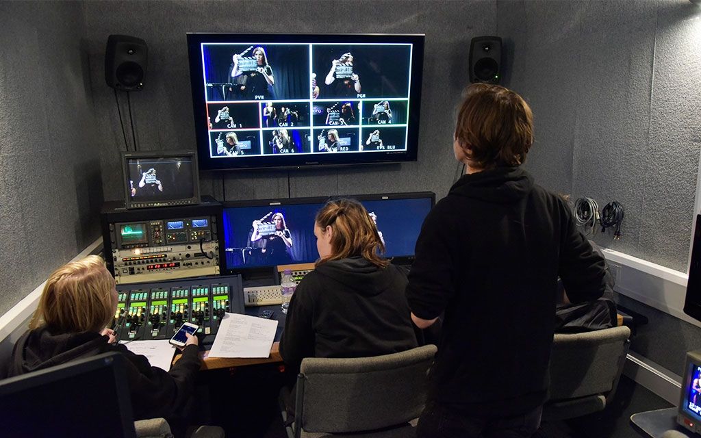 Three students in a tv studio looking at the tv screen