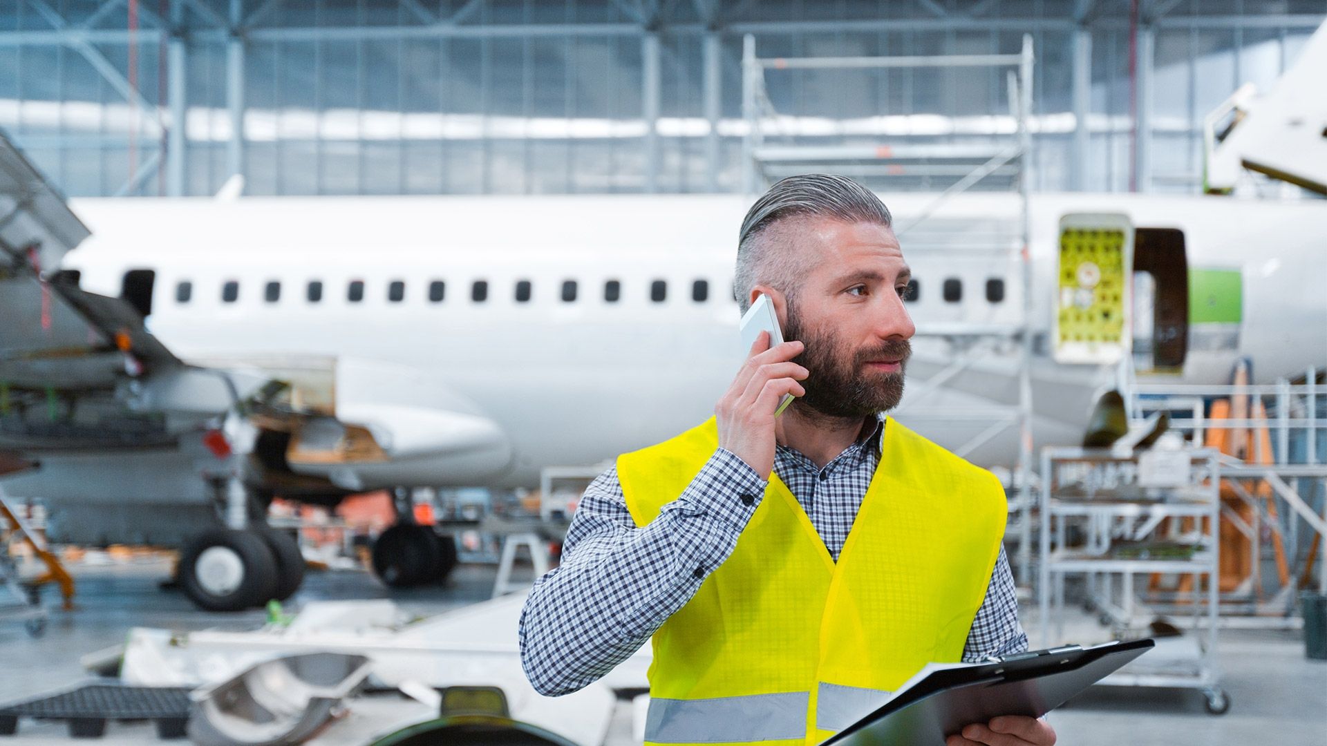 Source Aircraft engineer talking on mobile phone in a hangar