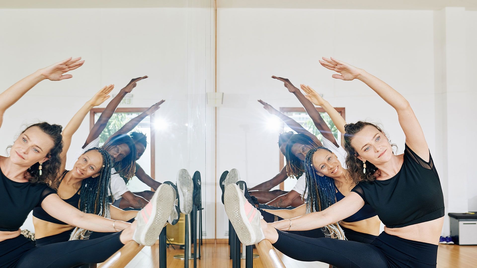 Two female and two male dancers stretching in studio