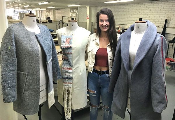 Fashion Design student Corran standing next to her three mannequins, all modelling her work 