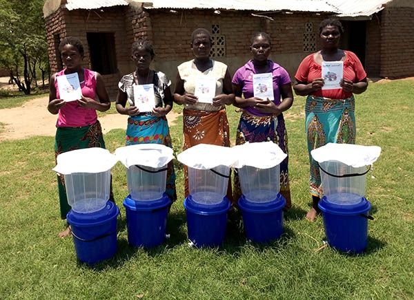 Five people stood in front of buckets ready to collect clean drinking water