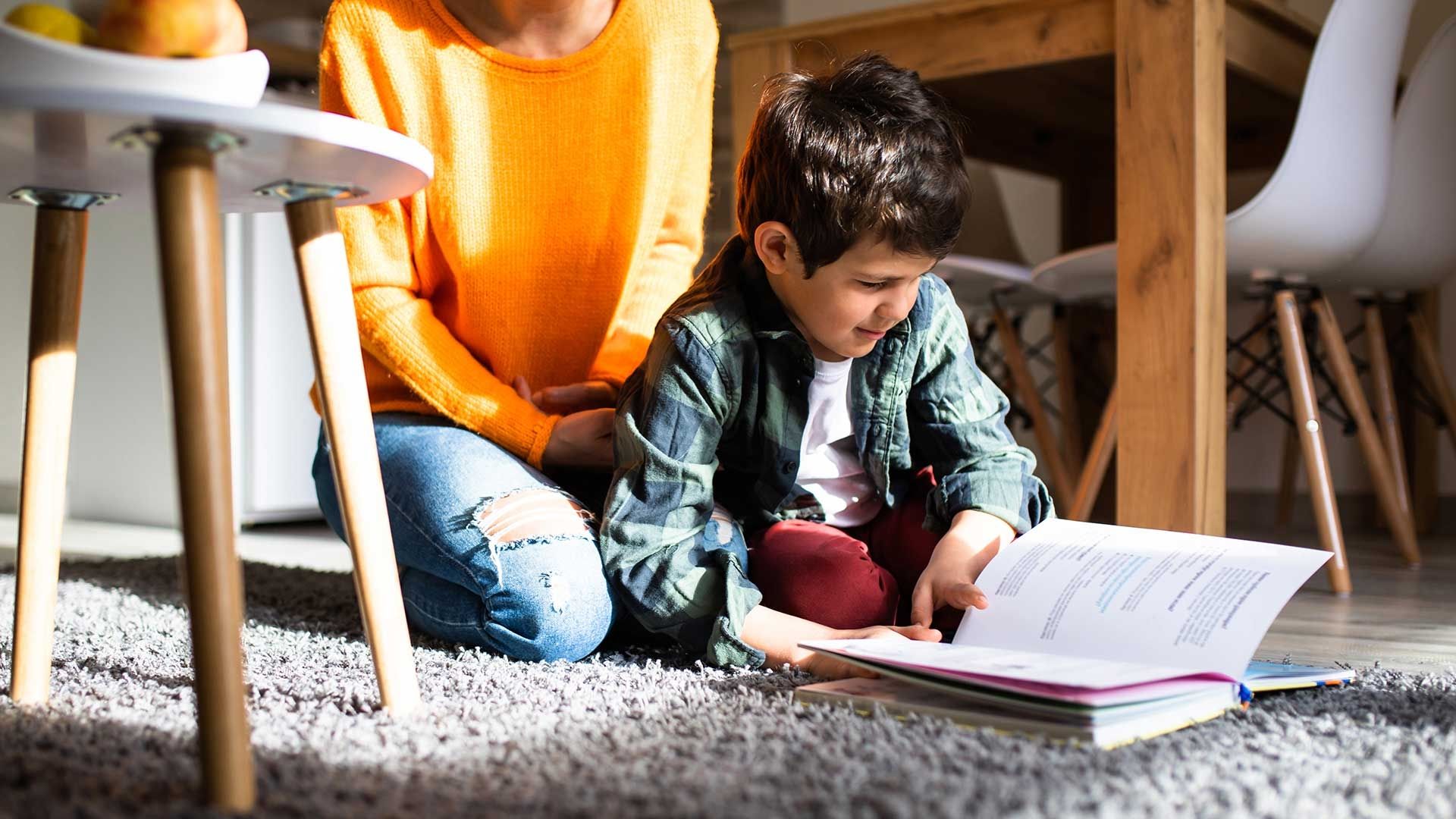 Small child reading a book on floor with lady figure