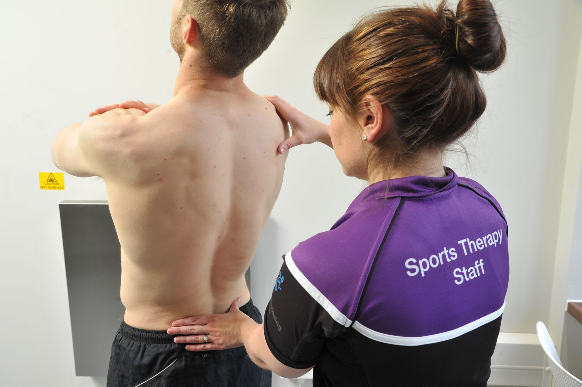 A sports therapy student attends to a male in the wellbeing clinic