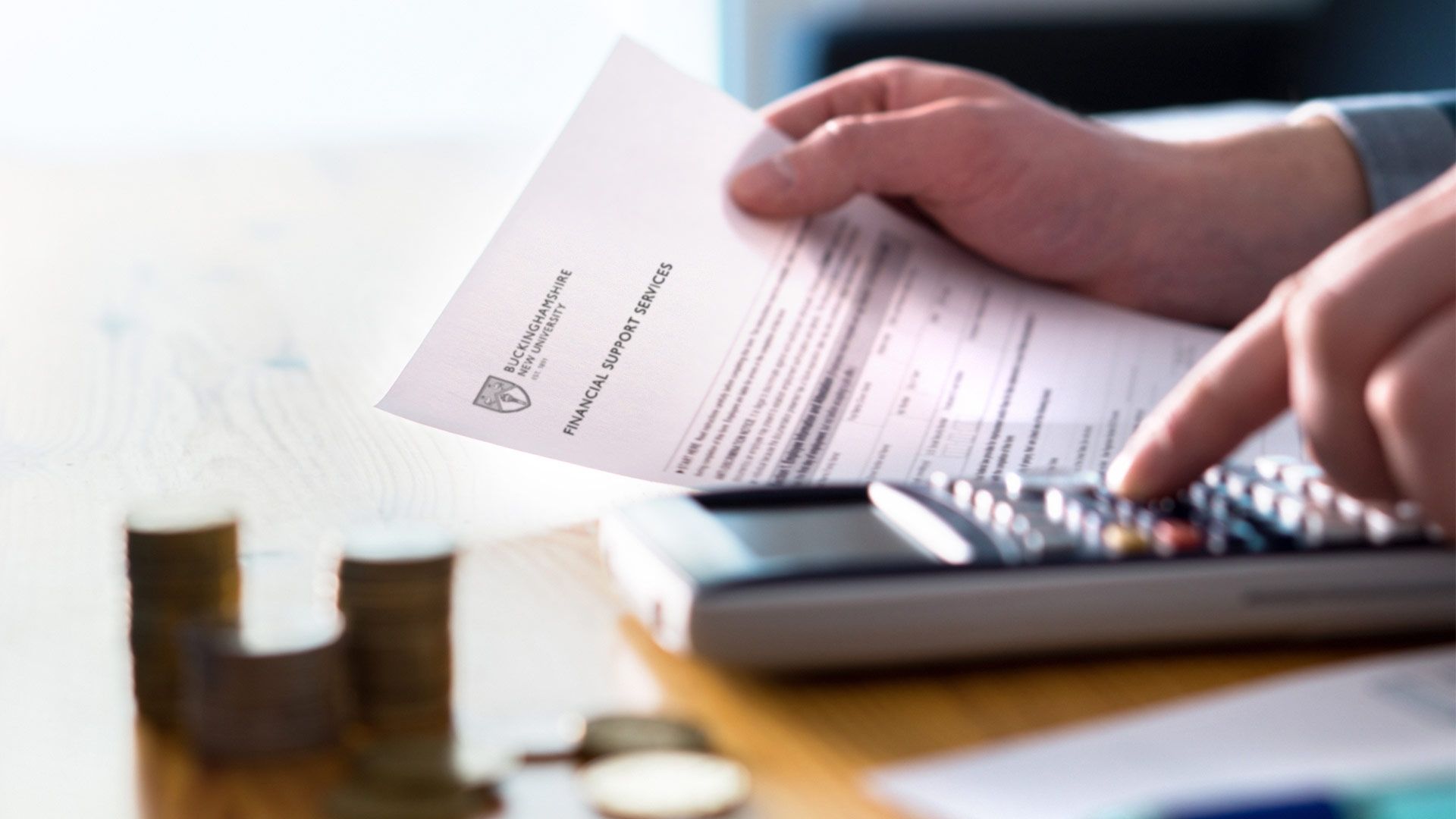 hands using a calculator and holding a BNU financial support document