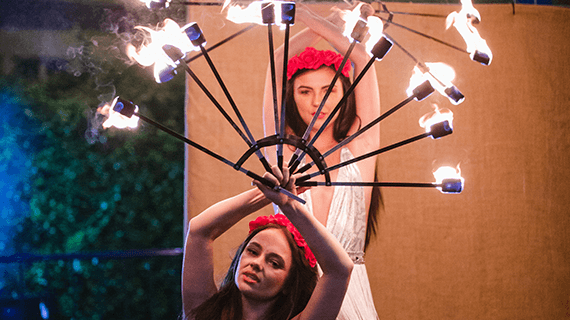Two women holding sticks of fire above their heads as part of a BNU Festiball student event