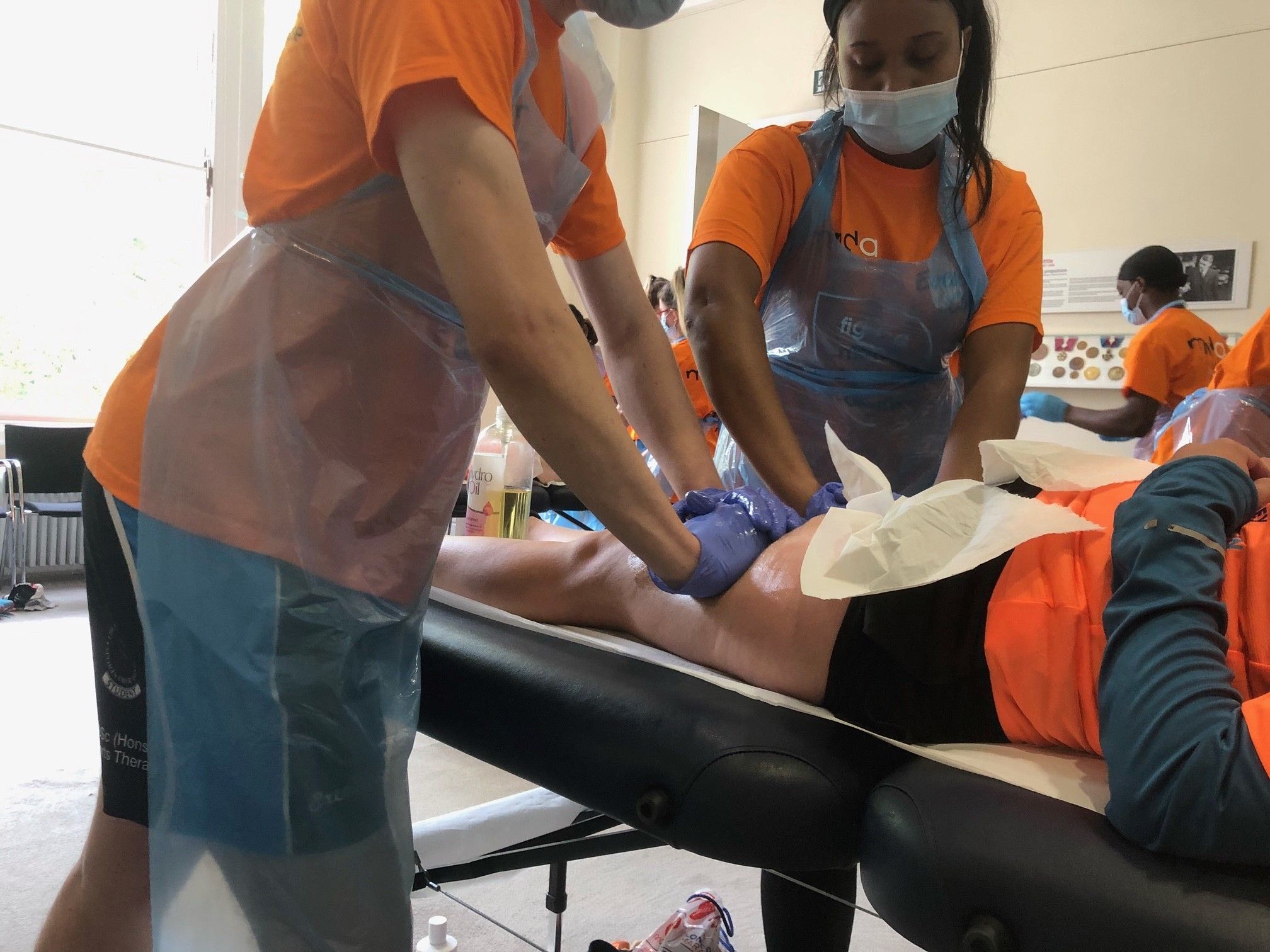 Students in MNDA uniform and PPE carrying out sports therapies on athletes