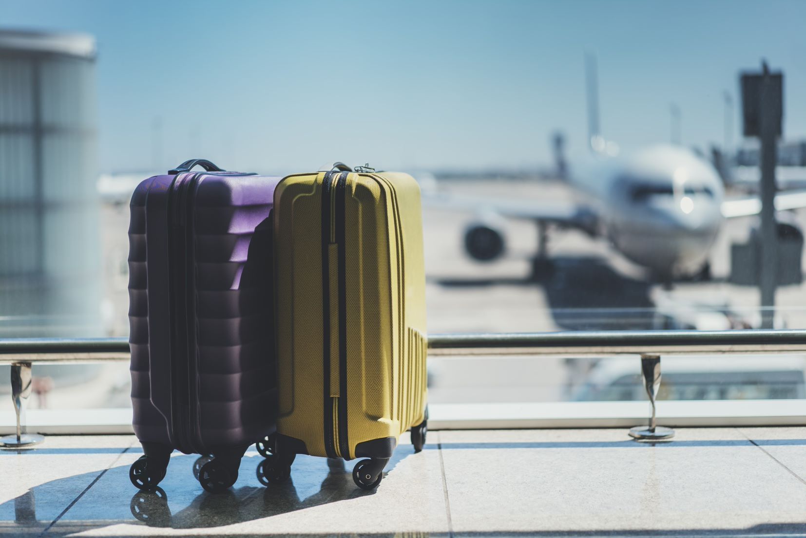 two suitcases in an airport with plane in the background