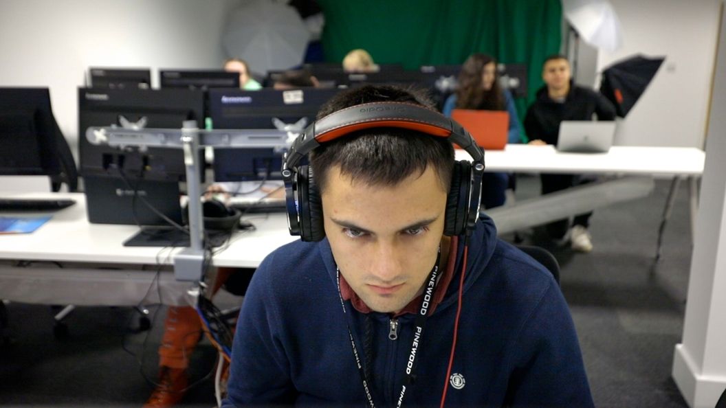 Male student wearing headphones while working at BNU based at Pinewood Studios