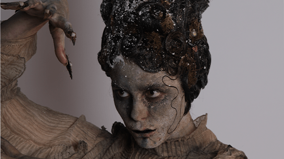 A BNU Hair and Make-up student with an ash-effect face paint applied whilst holding their right hand up in the air.