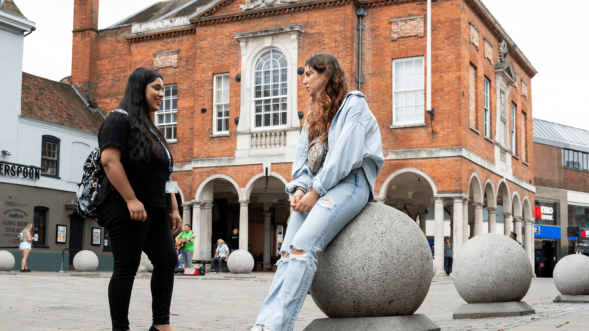 Two students facing one another stood talking in the centre of High Wycombe