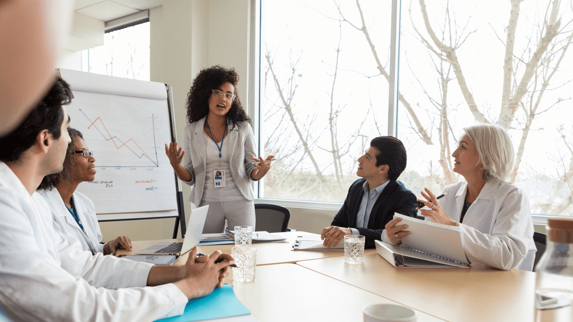 Business meeting amongst five members of staff sat around a table