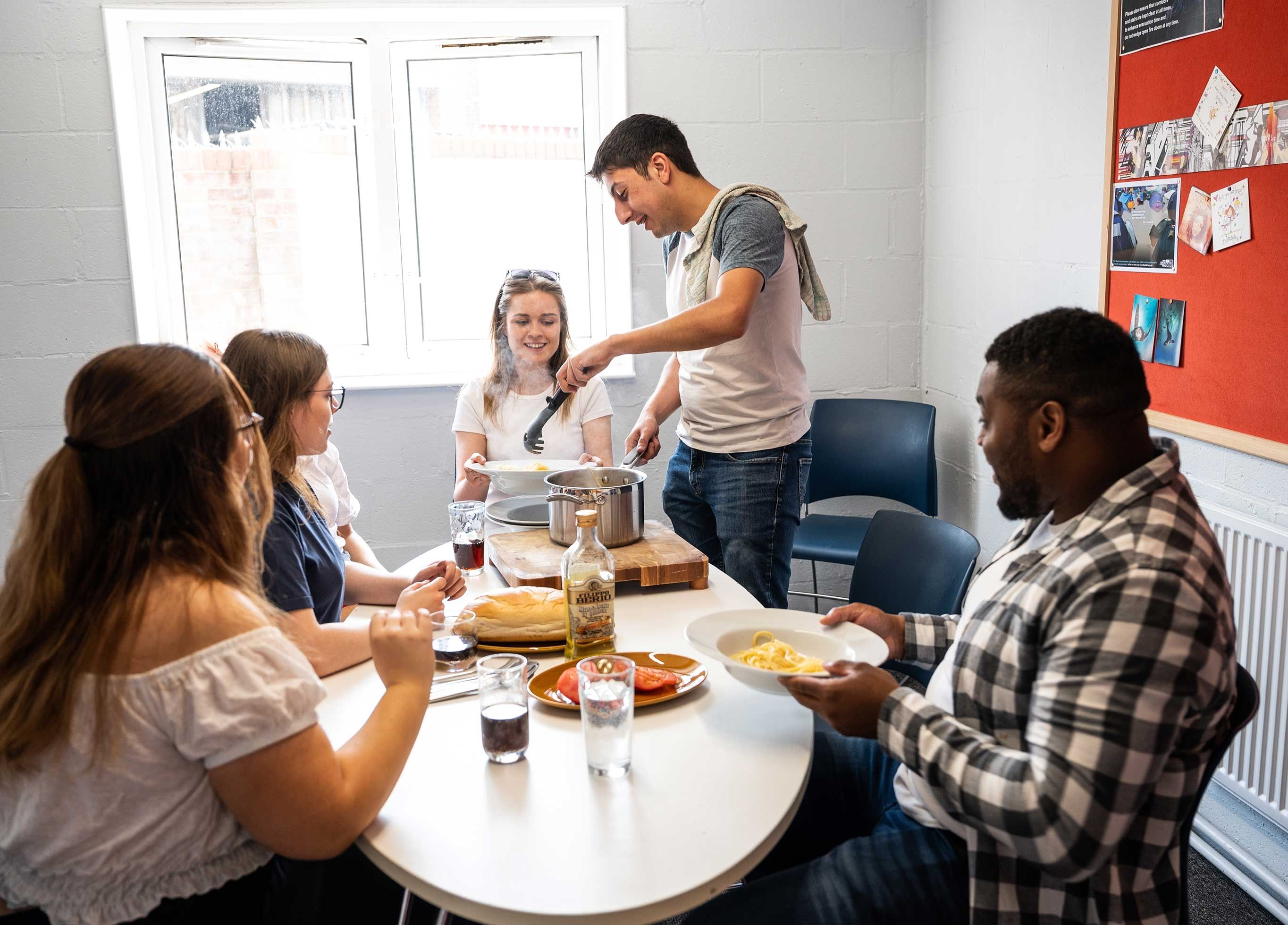 5 students sitting around a table in a Brook Street kitchen eating dinner