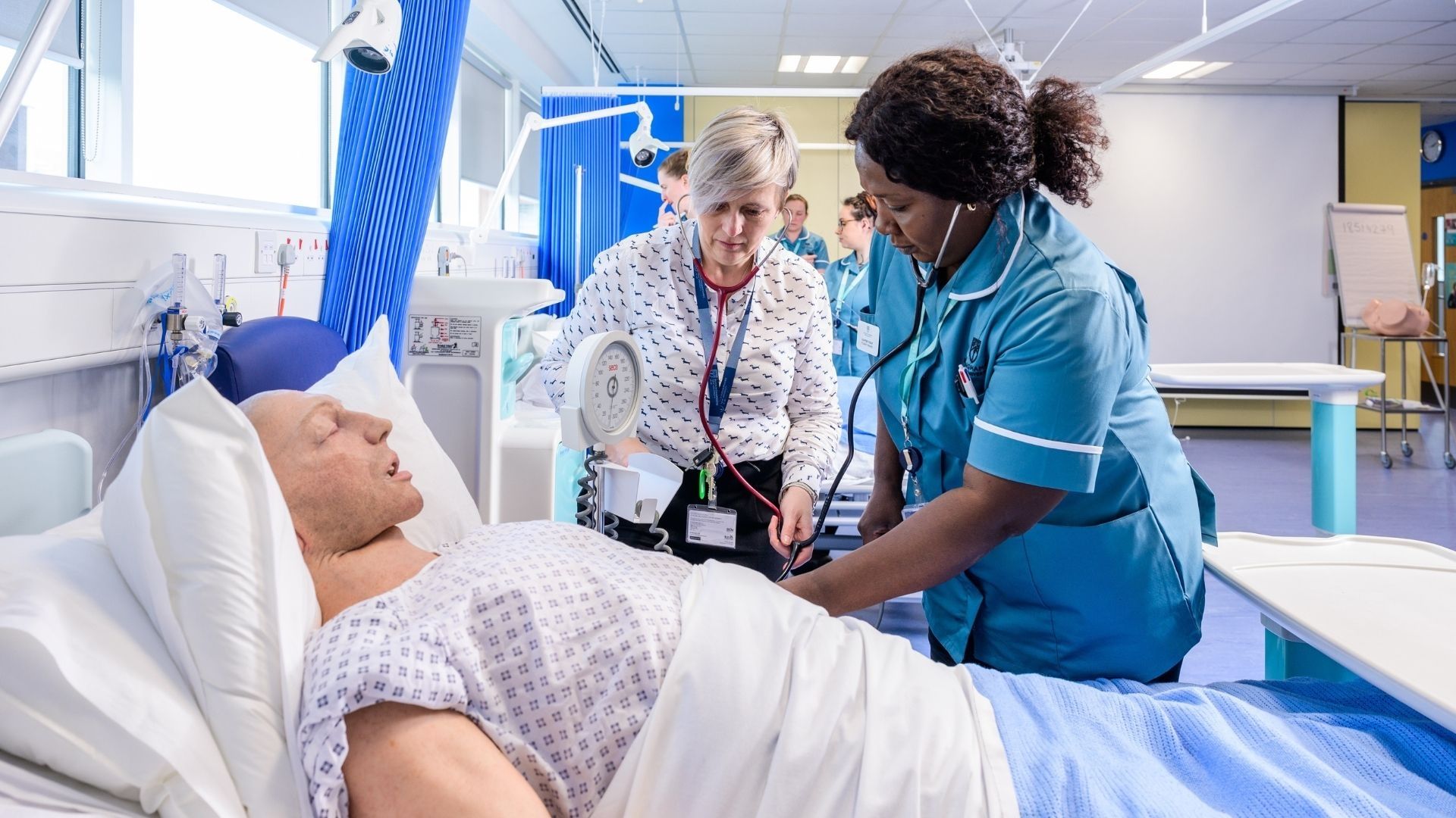 A BNU student nurse alongside a hospital bed which has a male dummy in