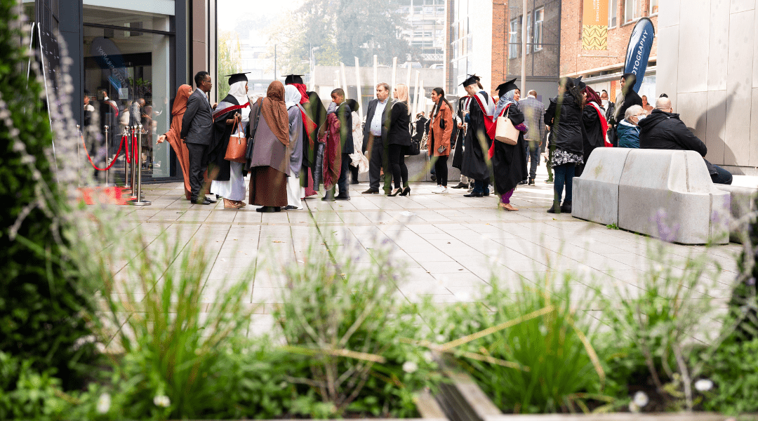 Graduates on the concourse with their friends, family, and loved ones