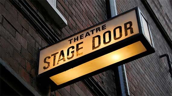 A sign outside a building saying 'stage door' 