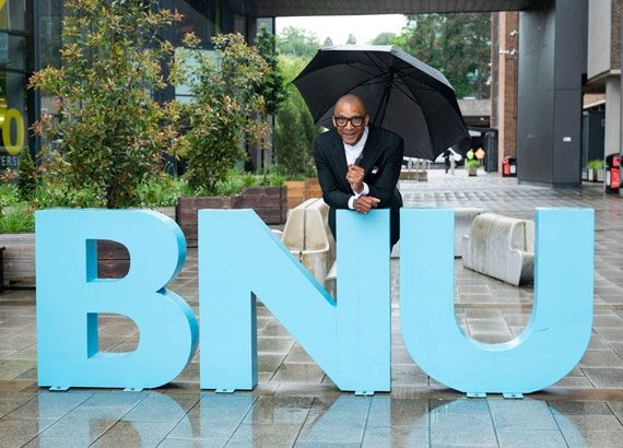 Jay Blades stood with an umbrella behind the BNU letters on the concourse