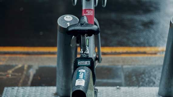 A bicycle locked into a stand on a pavement.