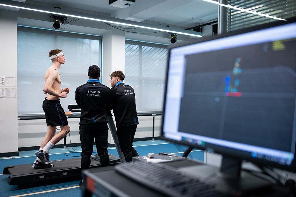 A student on a treadmill whilst two Sports Therapy students monitor his heart rate