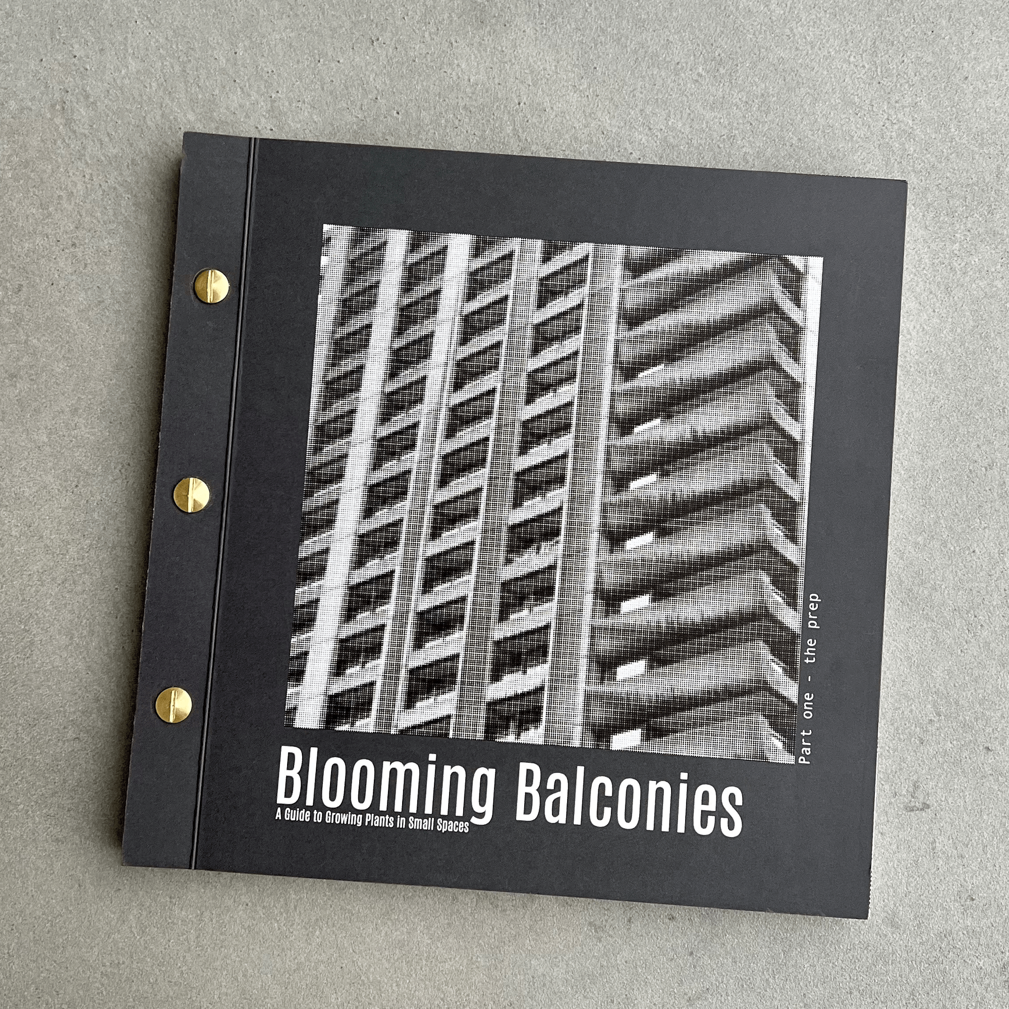 A closed book with the front of the book showing a tower block with the wording "Blooming Balconies".