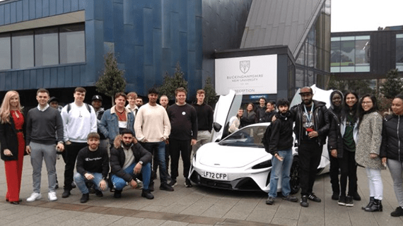 A group of 24 Business and Law students stood either side of a white McLaren sports car by the Gateway building.