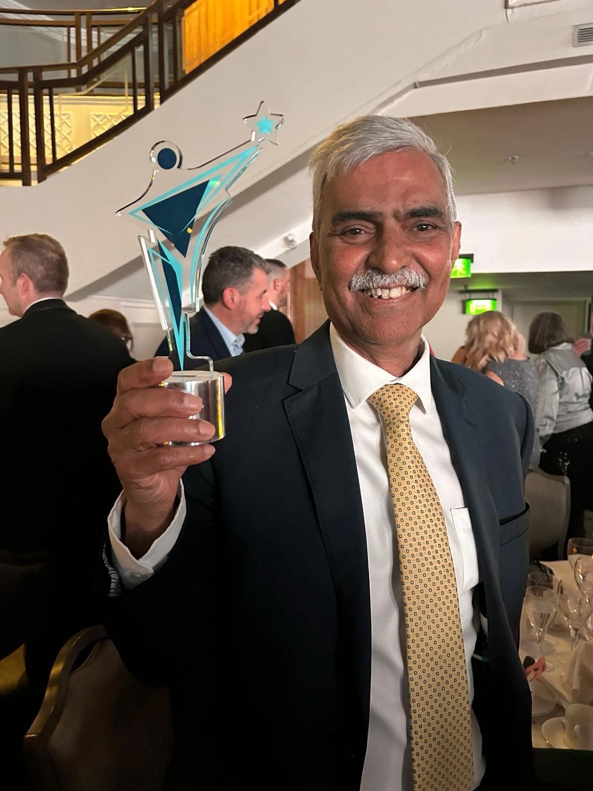 Mike holds his award and smiles