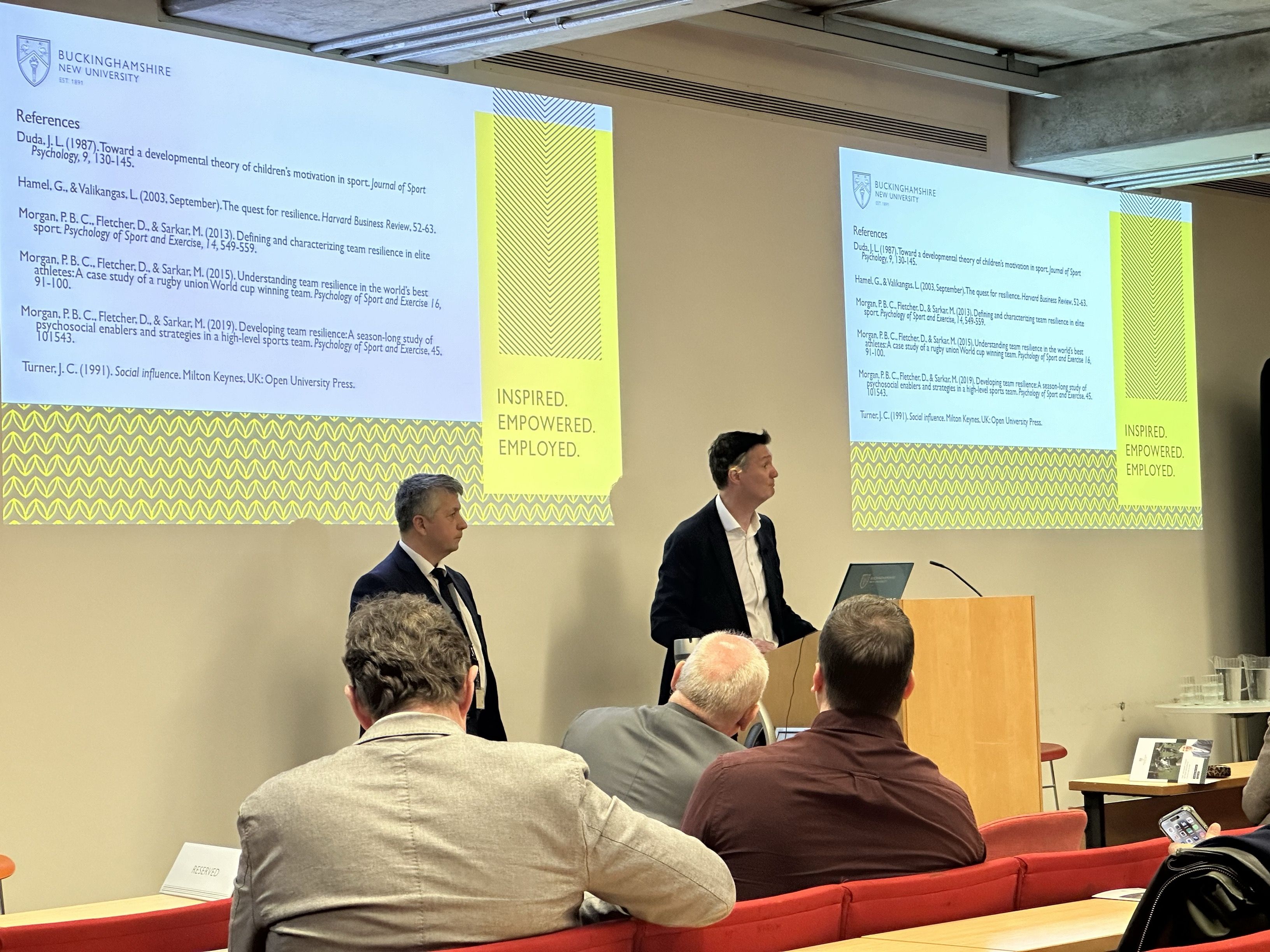 Professor Paul Morgan and Professor Florin Ioras stand at podium