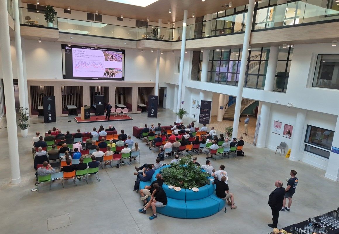 Room filled with people all sat around tables