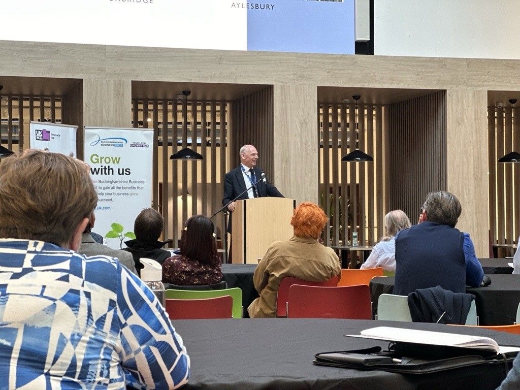 Professor Nick Braisby stands at podium and presents to delegates
